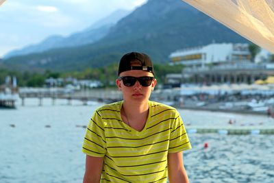 Portrait of man wearing sunglasses standing against mountain