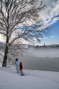 Bare trees on snow against sky during winter