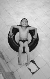 High angle view of smiling boy lying on inflatable ring in swimming pool