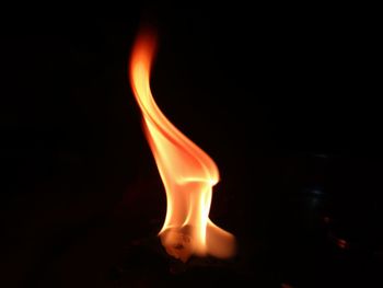 Close-up of burning candle against black background