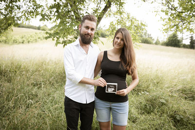 Portrait of smiling couple standing on field