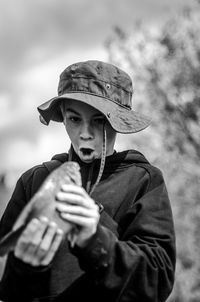 Shocked boy looking at fish while standing against sky