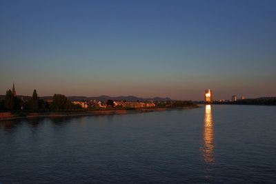 Illuminated city buildings against clear sky at sunset