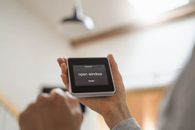 Mid adult woman holding smart home automation device with text