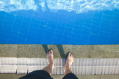 Low section of man standing by swimming pool