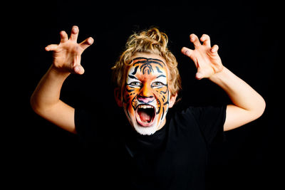 Close-up of man with face paint against black background