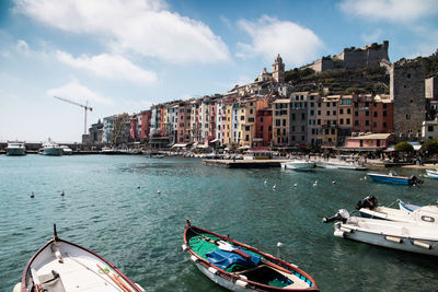 Boats moored at harbor by buildings in city