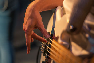 Midsection of man playing bass guitar