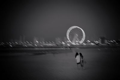 Blurred motion of ferris wheel in city against sky