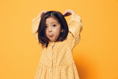 Portrait of young woman against yellow background