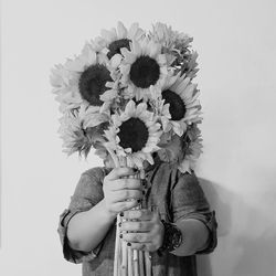 Low angle view of woman holding flowering plant against white background