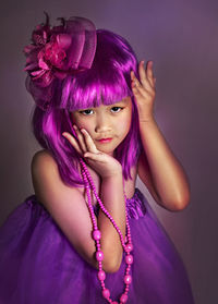 Portrait of cute girl standing against purple background