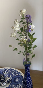 Close-up of flower vase on table against wall at home