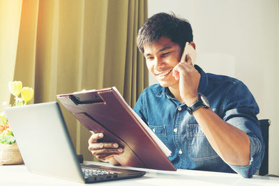 Man using mobile phone while sitting on table