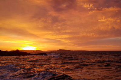 Scenic view of sea against dramatic sky during sunset