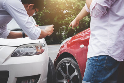 Midsection of man and woman standing by car