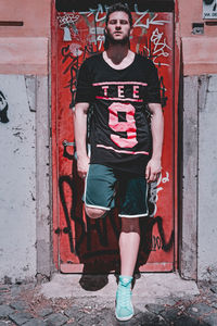 Portrait of young man standing against door