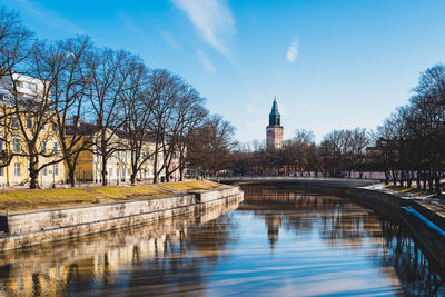 Buildings by river against sky