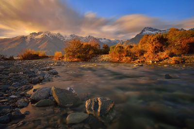 Scenic view of stream against sky during sunset