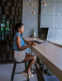 Side view of woman using mobile phone at cafe