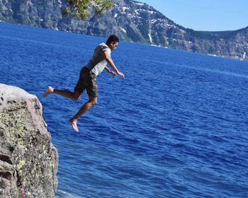 Side view of man jumping from cliff into sea