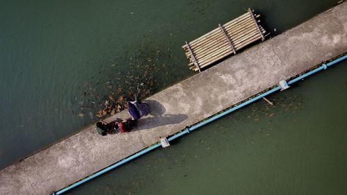 Aerial view of people sitting on pier over lake
