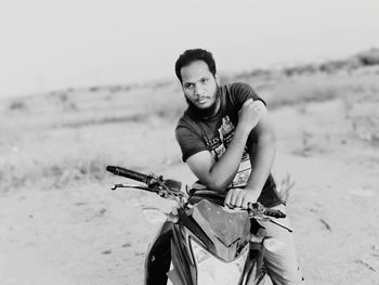 Man looking away while sitting on motorcycle against sky