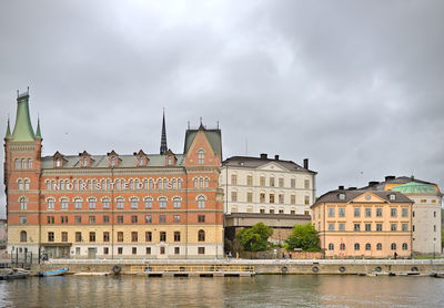 Buildings by river against sky