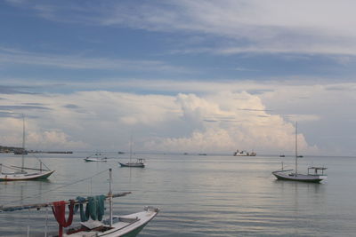 Sailboats in sea against sky