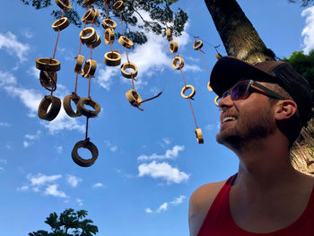 Low angle view of smiling man wearing sunglasses and cap against sky