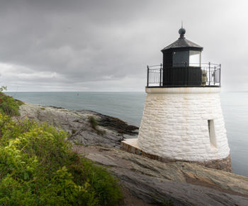 Lighthouse by sea against sky