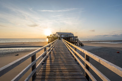 Pier over sea against sky during sunset