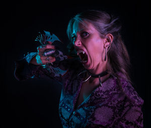 Portrait of spooky woman standing against black background