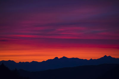 Scenic view of silhouette mountains against orange sky