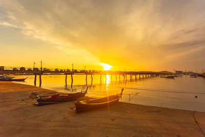 Boats moored in sea at sunset