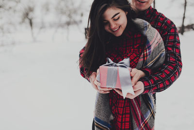 Boyfriend giving a gift box present with ribbon outdoor due to saint valentine day to her girlfriend