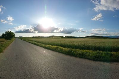 Road amidst field against sky