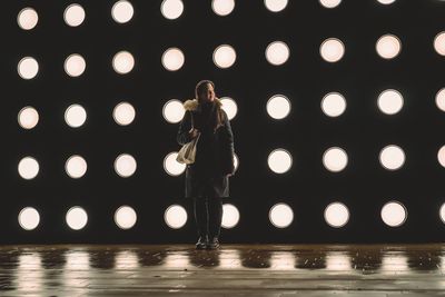 Low section of woman standing in illuminated water at night