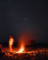 People and campfire against star field at desert