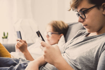 Boys using mobile phone while sitting on sofa