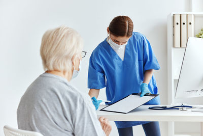 Rear view of woman using smart phone on table