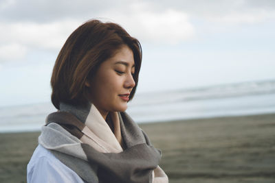 Beautiful young woman on beach against sky