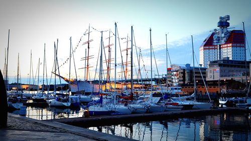 Sailboats moored in harbor against clear sky