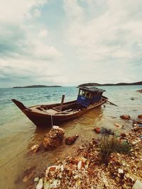 Boat moored on sea shore against sky