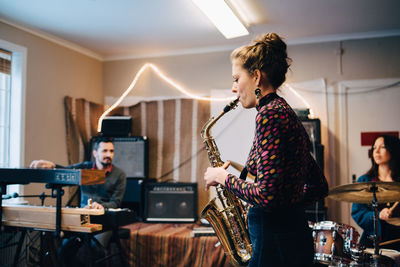 Friends playing various instruments while practicing at recording studio