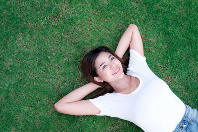 High angle portrait of woman lying on grassy field