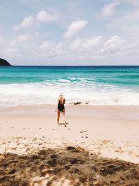 Rear view of boy on beach against sky