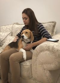 Young woman with dog sitting on sofa