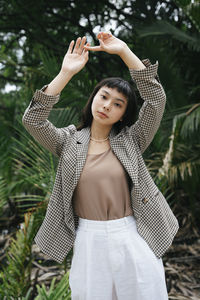 Full length of young woman standing against plants