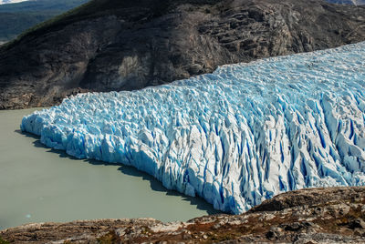 Scenic view of grey glacier flowing through rocks